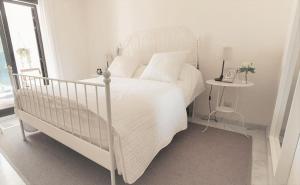 a white bed in a white bedroom with a table at La Alcaidesa Valerie Bruno in San Roque +29 photos