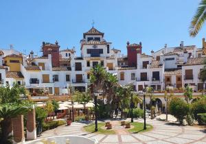 a large white building with palm trees in front of it at La Alcaidesa Valerie Bruno in San Roque