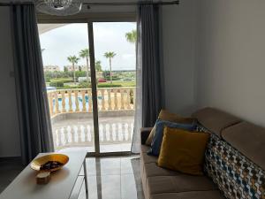 a living room with a couch and a large window at Holiday Mandria apt with pool in Paphos