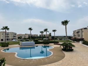 a swimming pool with a bench and palm trees at Holiday Mandria apt with pool in Paphos