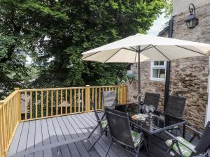 una terraza de madera con mesa y sombrilla en The Lantern en Kendal