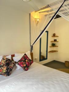 a bedroom with a white bed with two pillows at Karanga Bungalows in Michamvi