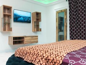 1 dormitorio con 1 cama y TV en la pared en Luxury home with class, en Accra