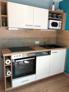 una cucina con mobili bianchi e un forno a piano cottura di Ferienhaus "Buddelschiff" a Ueckermünde