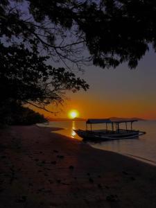 um par de barcos na praia ao pôr do sol em Palmyra Indah Bungalows em Sekotong