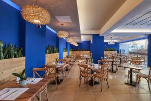 a restaurant with blue walls and wooden tables and chairs at Asana Hotel in Hersonissos