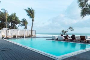 a swimming pool with chairs and the ocean at Mosvold Villa in Ahangama