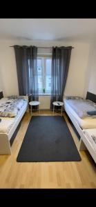 Duas camas num quarto com uma janela e um tapete em Moderne Monteurzimmer Vu em Dortmund