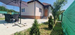 a patio with a table and an umbrella in front of a house at Casa Emy in Râmnicu Vâlcea
