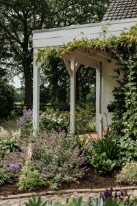 a white pergola in a garden with flowers at Boutique B&B Erve Hasselo in Vorden