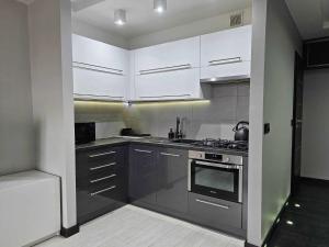 una cocina con electrodomésticos de acero inoxidable y armarios blancos en Apartament w centrum miasta z balkonem, en Jastrzębie-Zdrój