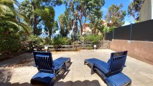 two blue chairs sitting on a patio with trees at Panoramer in Théoule-sur-Mer