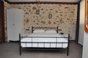 a bed in a bedroom with a stone wall at La Casa Carina Butik Otel in Antalya
