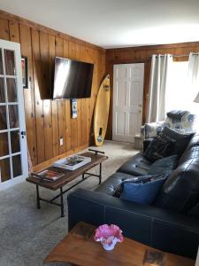 a living room with a black leather couch and a surfboard at Farmhouse 316 of Milton in Milton