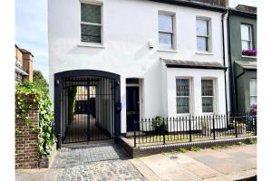 une maison blanche avec une porte noire dans l'établissement The Banfield Park Wonder - Lovely 3BDR Flat with Parking and Patio, à Londres