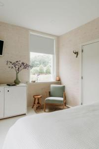 a bedroom with a bed and a chair and a window at Boutique B&B Erve Hasselo in Vorden