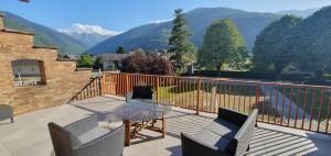 a balcony with a glass table and chairs and mountains at Maison de la Lionne in Luchon