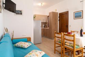 a living room with a blue couch and a kitchen at Akrotiri Apartments in Makry Gialos