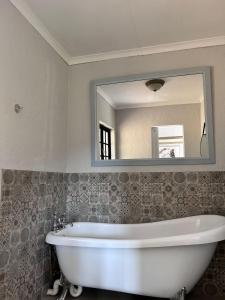 a white bath tub in a bathroom with a mirror at Silver Mist Resort in Haenertsburg