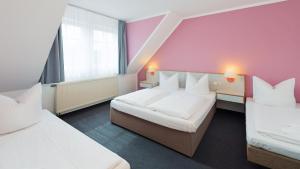 um quarto de hotel com duas camas e uma parede rosa em Motel Hormersdorf em Hormersdorf