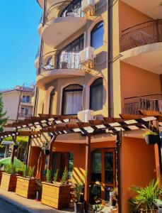 an orange building with awnings and plants in front of it at Алми Almi in Sveti Vlas