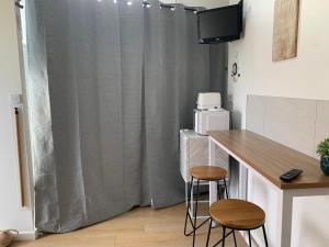 a kitchen with a table and two stools in front of a curtain at La Pose Normande in La Cerlangue