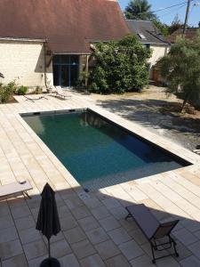 uma piscina com duas cadeiras ao lado de uma casa em Logis de charme en Touraine em Sainte-Maure-de-Touraine