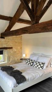 Cama grande en habitación con techo de madera en Gîte Le Perche Rose, en Eymet