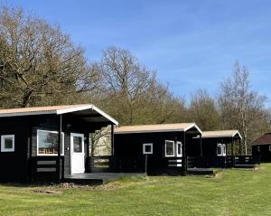 a black house with a porch and a grass field at Myrhoj Camping in Myrhøj