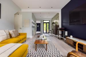 a living room with a yellow couch and a blue wall at The East Dulwich House in London