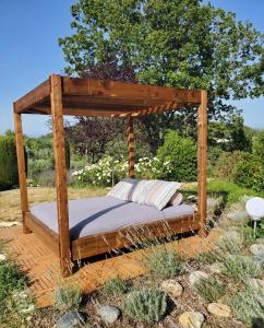 a bed under a wooden canopy in a garden at Le Jas des Cannebieres in Villeneuve
