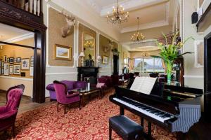 a living room with a piano and purple chairs at The Lake Hotel in Killarney