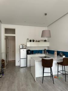 eine weiße Küche mit 2 Stühlen und einem Tisch in der Unterkunft Traum Wohnung mit Hauch Venedig/Kanal mit Kajak/Sauna/Fitness in Leipzig
