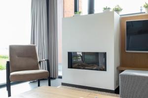 a living room with a fireplace and a chair and a tv at Villas Winterberg in Winterberg