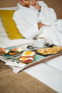 ヒホンにあるHotel Don Manuelのベッドの上に朝食用の食品のトレイ