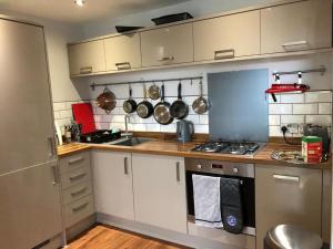 基督城的住宿－Charming 2-Bed Apartment in Christchurch，厨房配有白色橱柜以及带锅碗瓢盆的炉灶。
