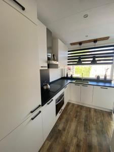 een keuken met witte kasten en een houten vloer bij Het Dirkbosje in Middelharnis