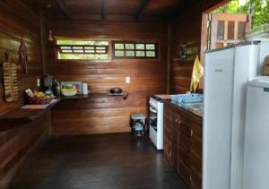 uma cozinha com paredes de madeira e um frigorífico branco em Recanto Shanti em Alter do Chão
