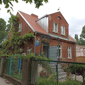 an old brick house with a fence in front of it at Seaside Holiday House in Gdańsk