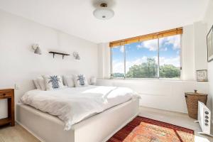 a white bedroom with a bed and a window at The Edward at Bondi - A Blissful Beachside Retreat in Sydney