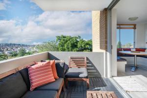 a patio with a couch and chairs on a balcony at The Edward at Bondi - A Blissful Beachside Retreat in Sydney