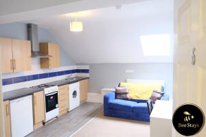 a kitchen and living room with a blue couch at Bee Stays - Crossbar Hotel One-Bedroom Flats in Warrington