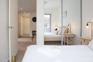 a white bedroom with a bed and a mirror at 'Perfectly Pyrmont' Sun-drenched Nordic Simplicity in Sydney