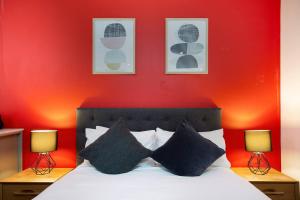 - une chambre dotée d'un mur rouge et d'un lit avec deux lampes dans l'établissement Ultra modern Inner-city Lifestyle in Darlinghurst, à Sydney