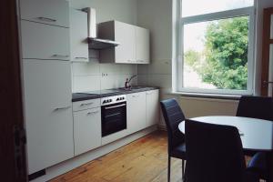 une cuisine avec des placards blancs, une table et une fenêtre dans l'établissement unique: 5 bedroom - 2 Bathroom - kitchen - central, à Bremerhaven