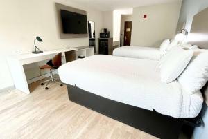 a hotel room with two beds and a desk and a television at Days Inn by Wyndham Arlington in Arlington