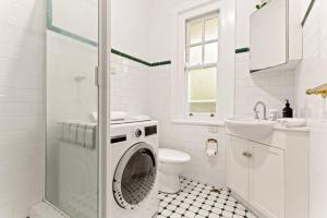 a white bathroom with a washing machine in the shower at 'Four Keeps' A Cosy North Sydney Wharf Hideaway in Sydney