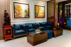 a living room with blue furniture and paintings on the wall at Victory Hotel in Hanoi