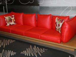 Sofá rojo con almohadas en una habitación en ibis Salvador Rio Vermelho, en Salvador