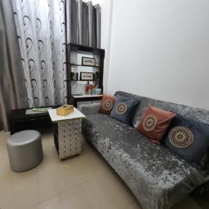 sala de estar con sofá gris con almohadas y mesa en Beach side Private Room for Travelers, en Sharjah